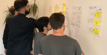 Photo of design concepts displayed on a wall (art gallery style) with voting dots